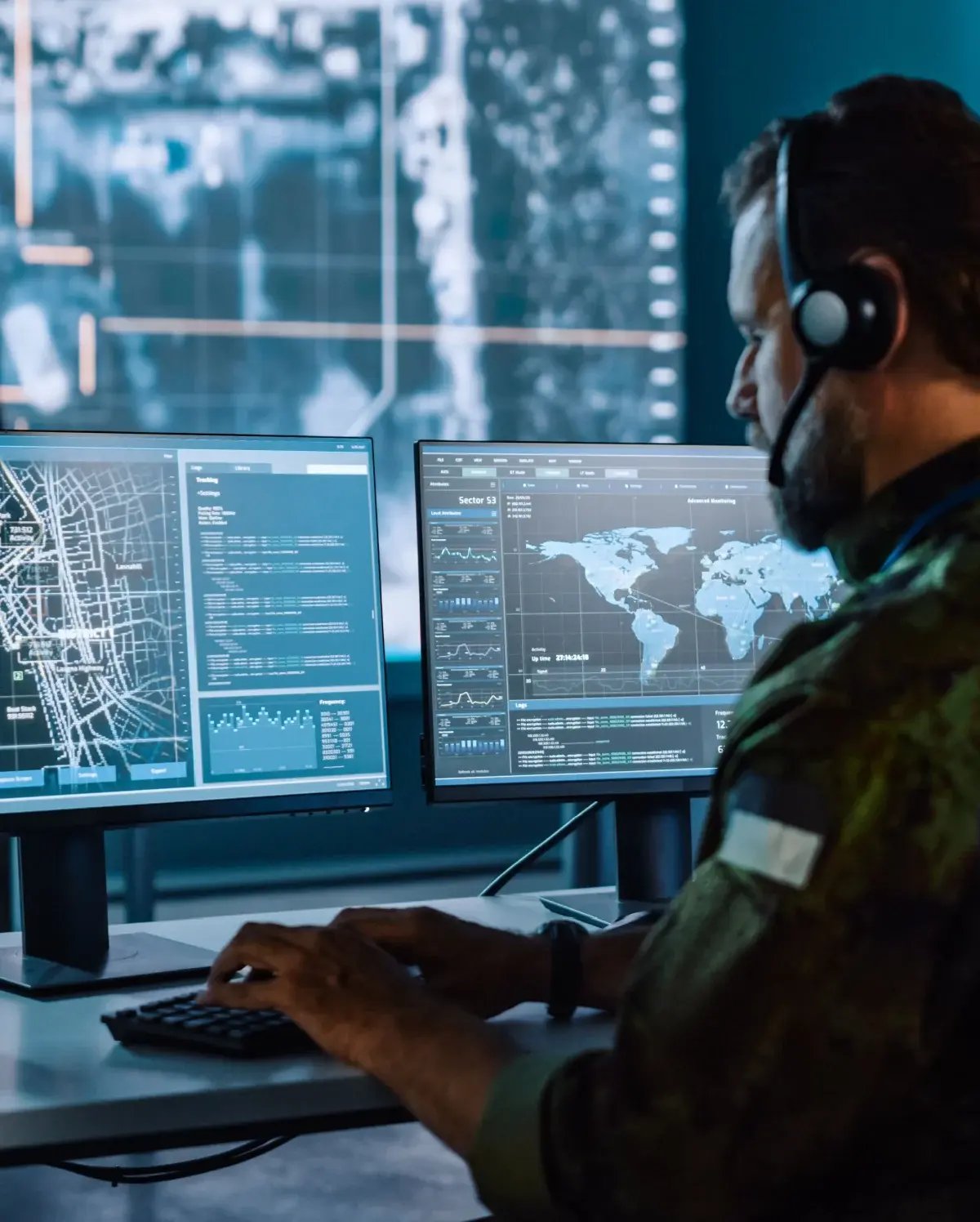 A military or security operator wearing a headset monitors multiple screens displaying world maps, data, and geographical information in a high-tech control room A military or security operator wearing a headset monitors multiple screens displaying world maps, data, and geographical information in a high-tech control room