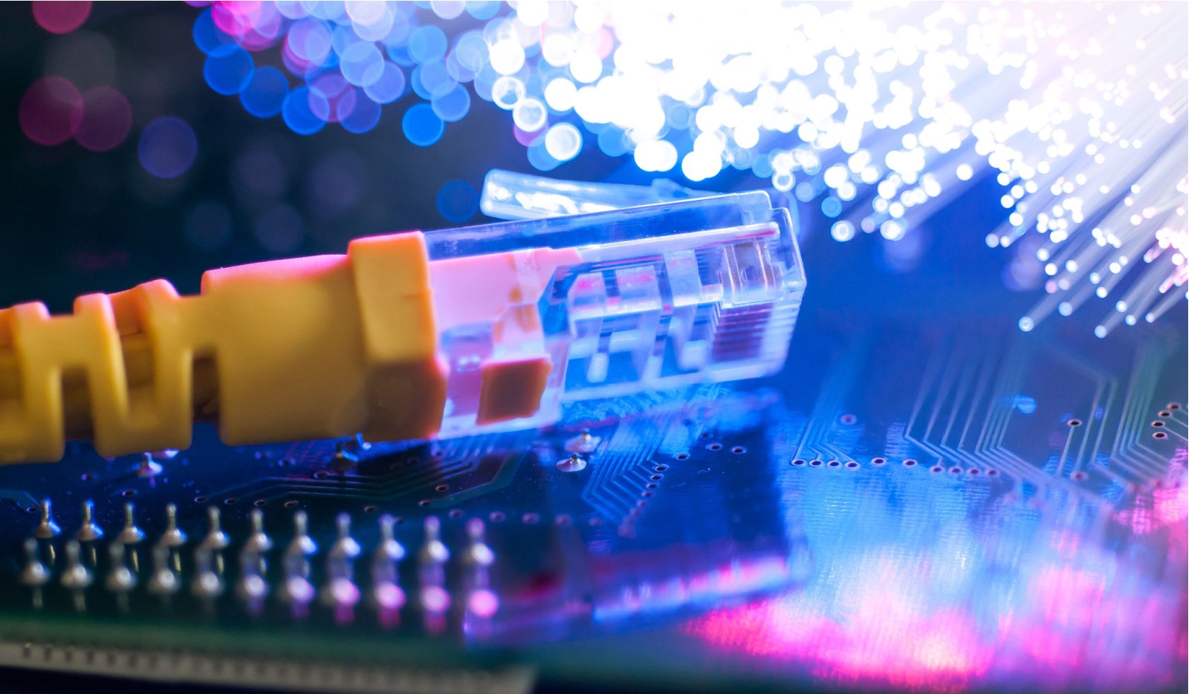 Yellow internet connection cable on circuit board, defocused optical fibre background.