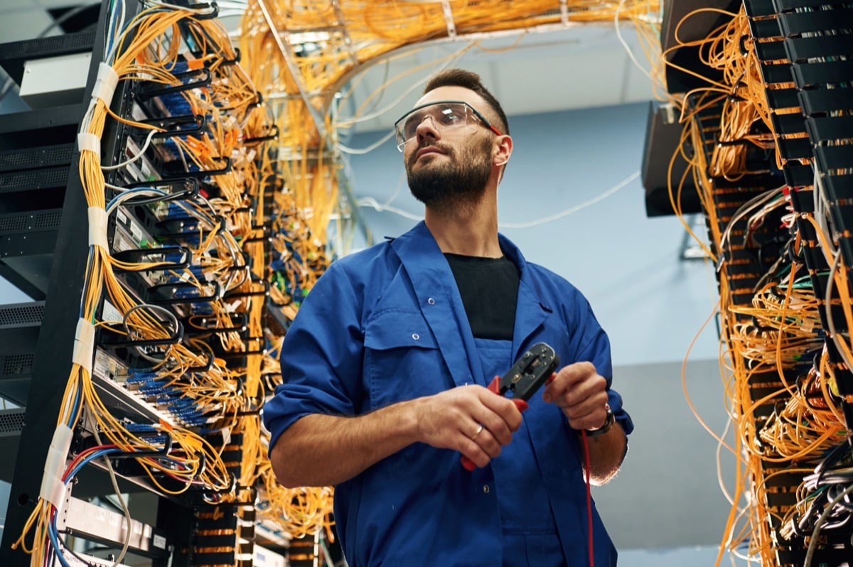 Comnet technician working on a network cable rack